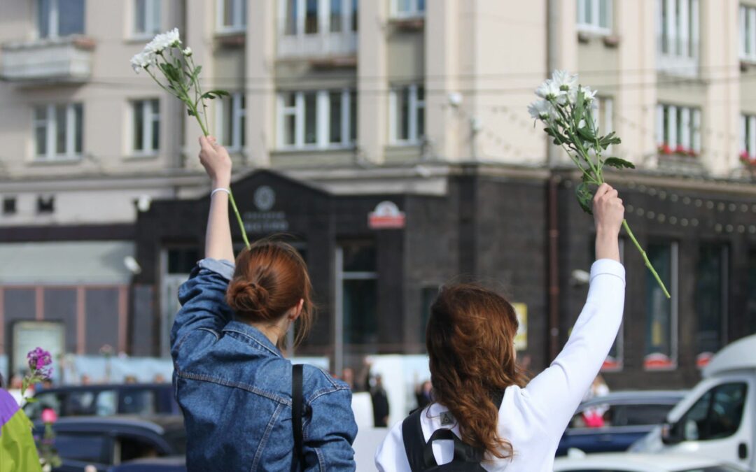 Mulheres com flores brancas nas mãos representando a cultura de paz.